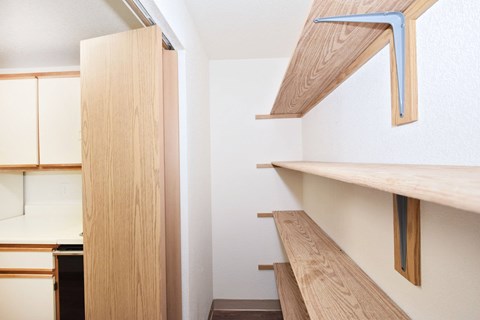 A kitchen with wooden cabinets and shelves.