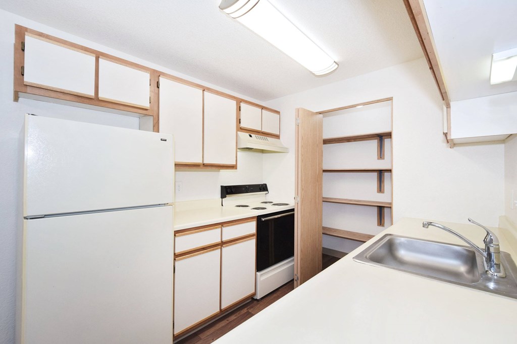 A kitchen with white appliances and wooden cabinets.