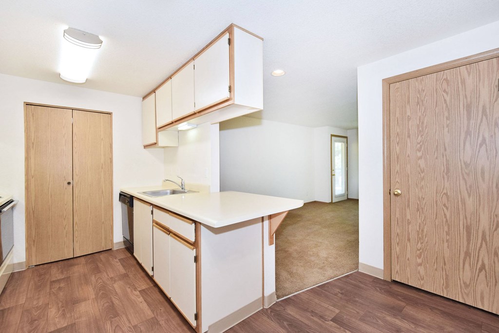 A kitchen with wooden floors and cabinets.