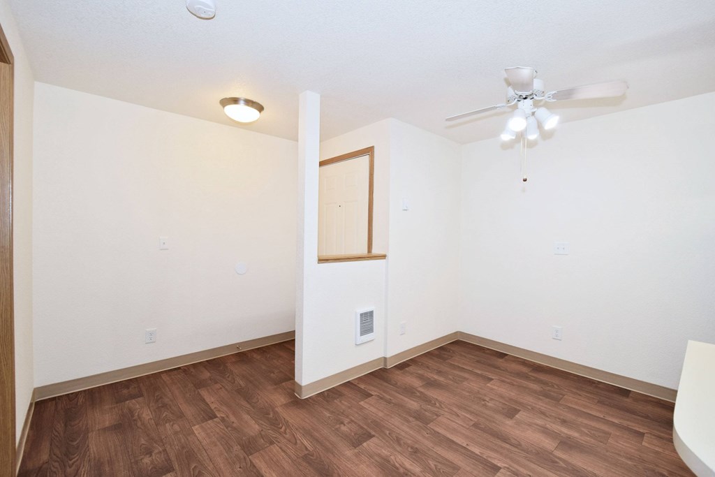 A room with a ceiling fan and wooden flooring.