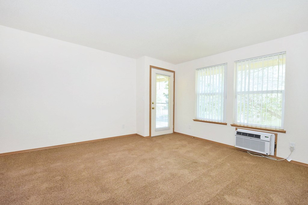 A room with a carpeted floor and a window with blinds.