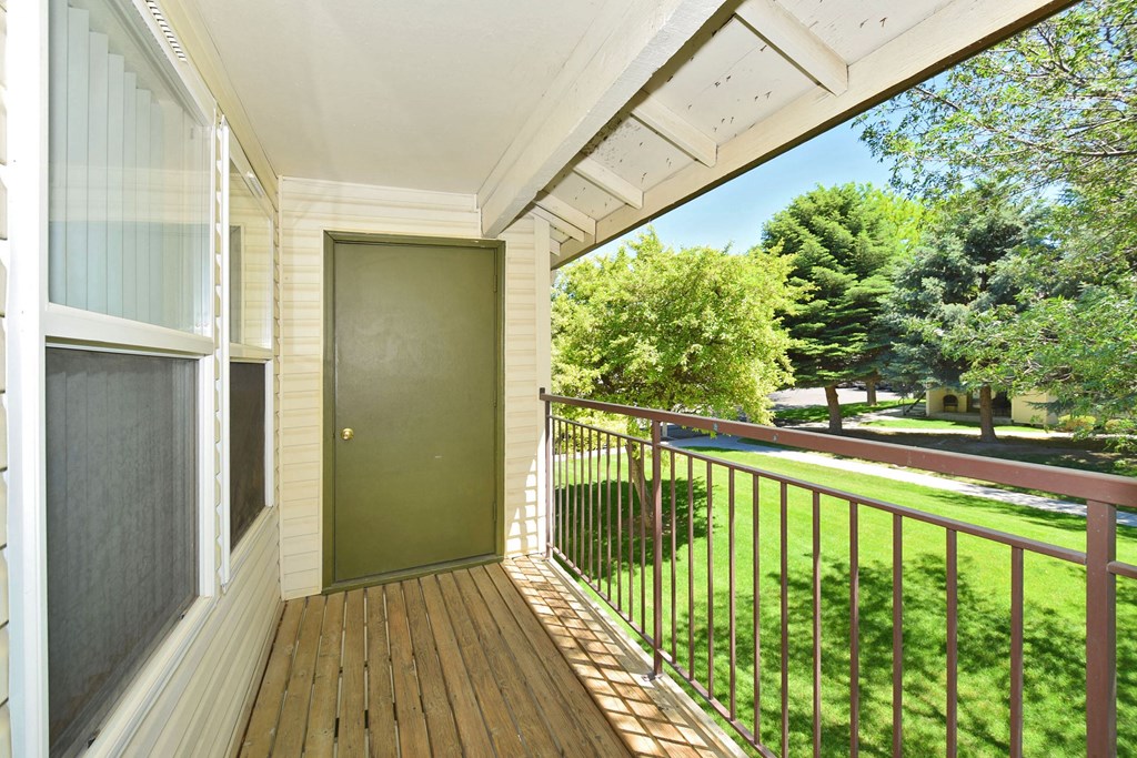 A balcony with a green door and a metal railing.
