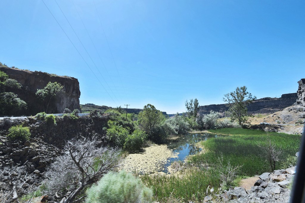 A river flows through a rocky landscape with greenery on the banks.