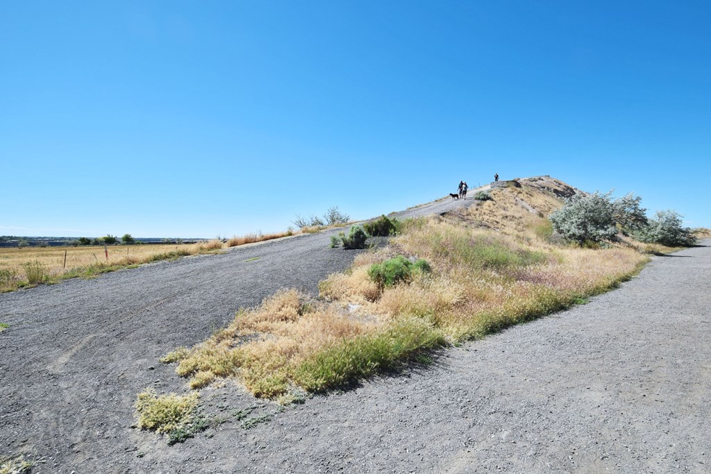 A road with a few people standing on the hill on the right side.