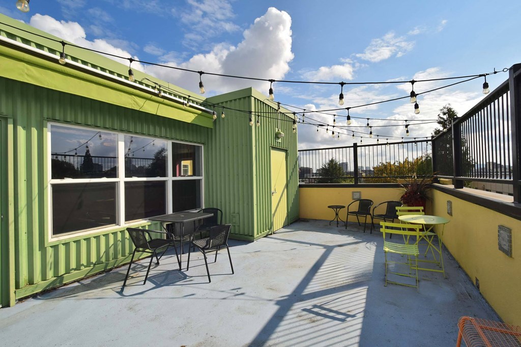 A patio with a table and chairs is surrounded by green walls.