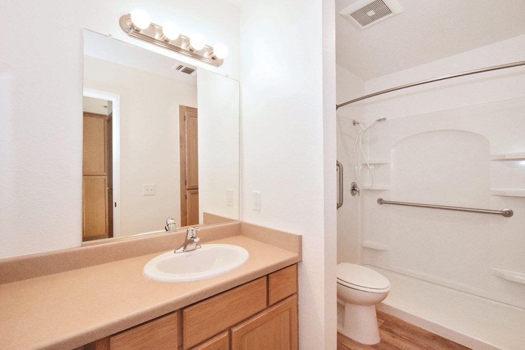 A bathroom with a sink, mirror, toilet and bathtub.