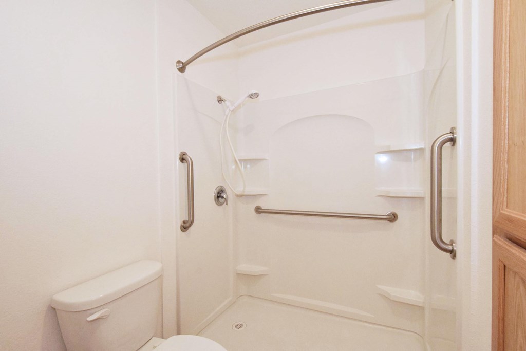 A white bathroom with a toilet, sink, and shower.