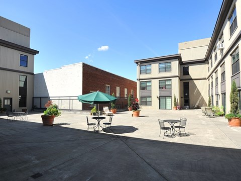 A courtyard with tables and chairs surrounded by buildings.