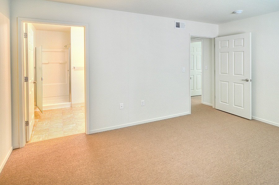 A room with a carpeted floor and two doors.
