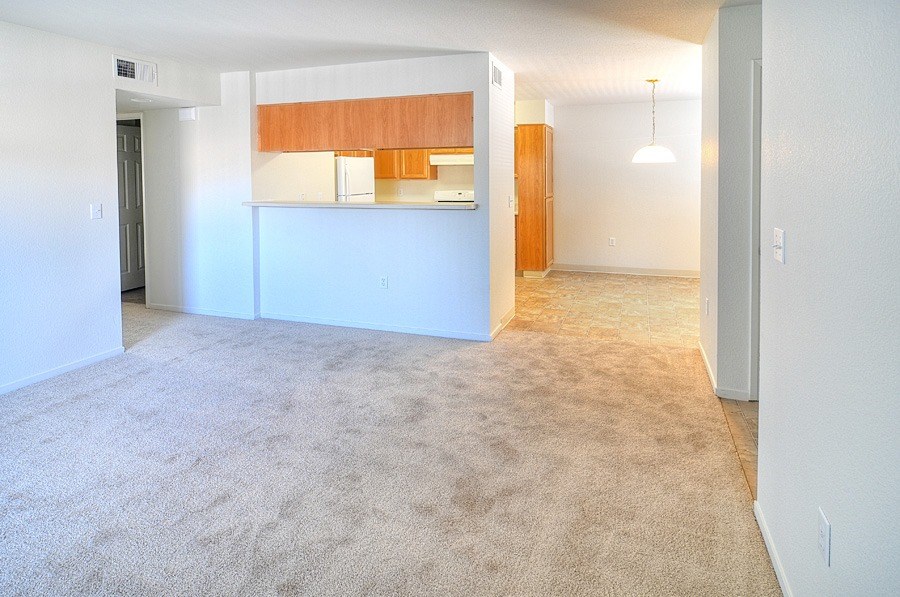 A carpeted room with a white wall and a wooden cabinet.