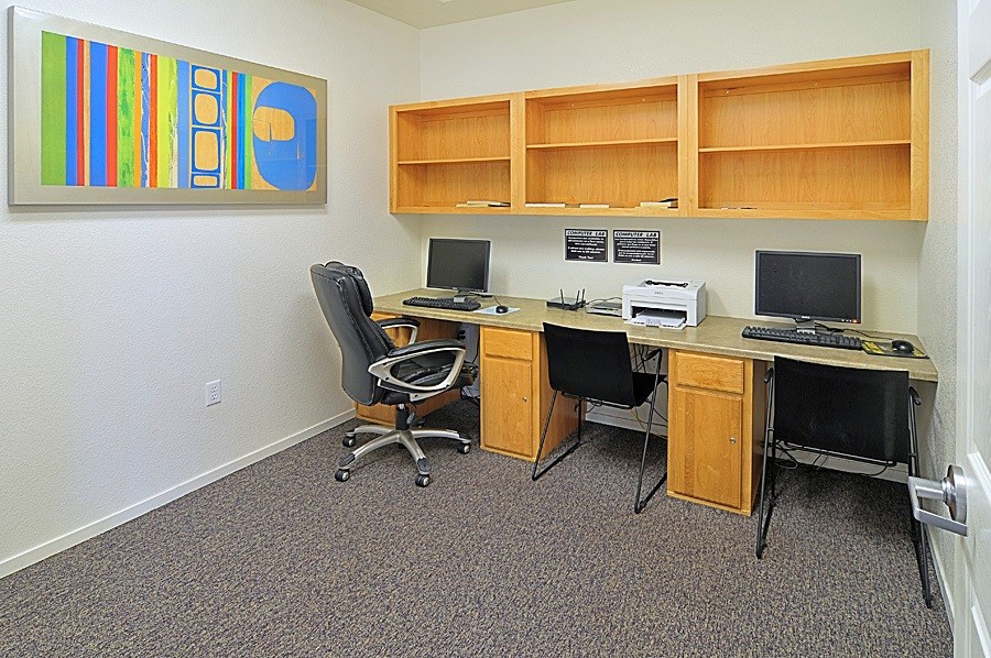 A room with a desk, chairs and a painting on the wall.