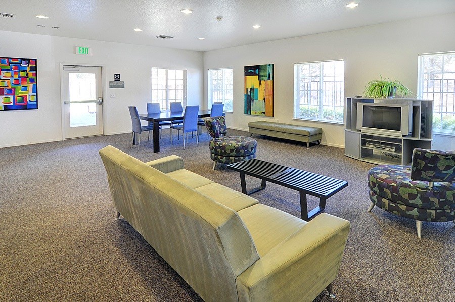 A room with a couch, chairs, and a television set.