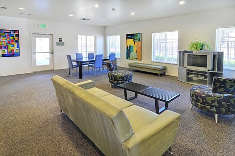 A room with a couch, chairs, and a television set.