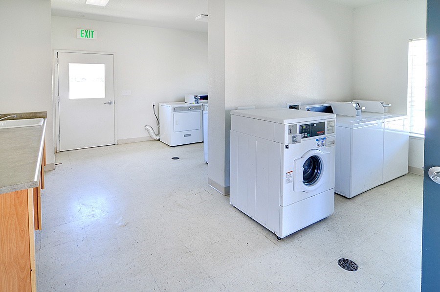 A laundry room with a washer and dryer and an exit sign.