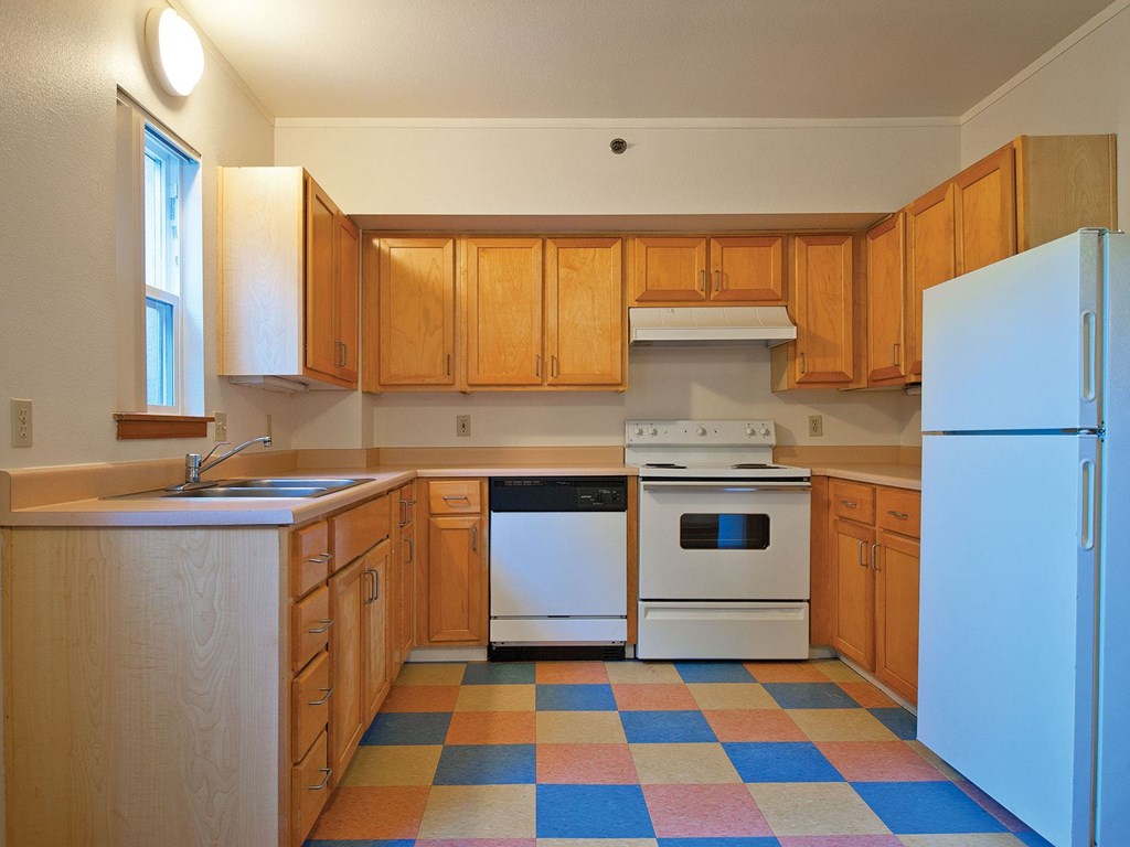 A kitchen with wooden cabinets and a checkered floor.