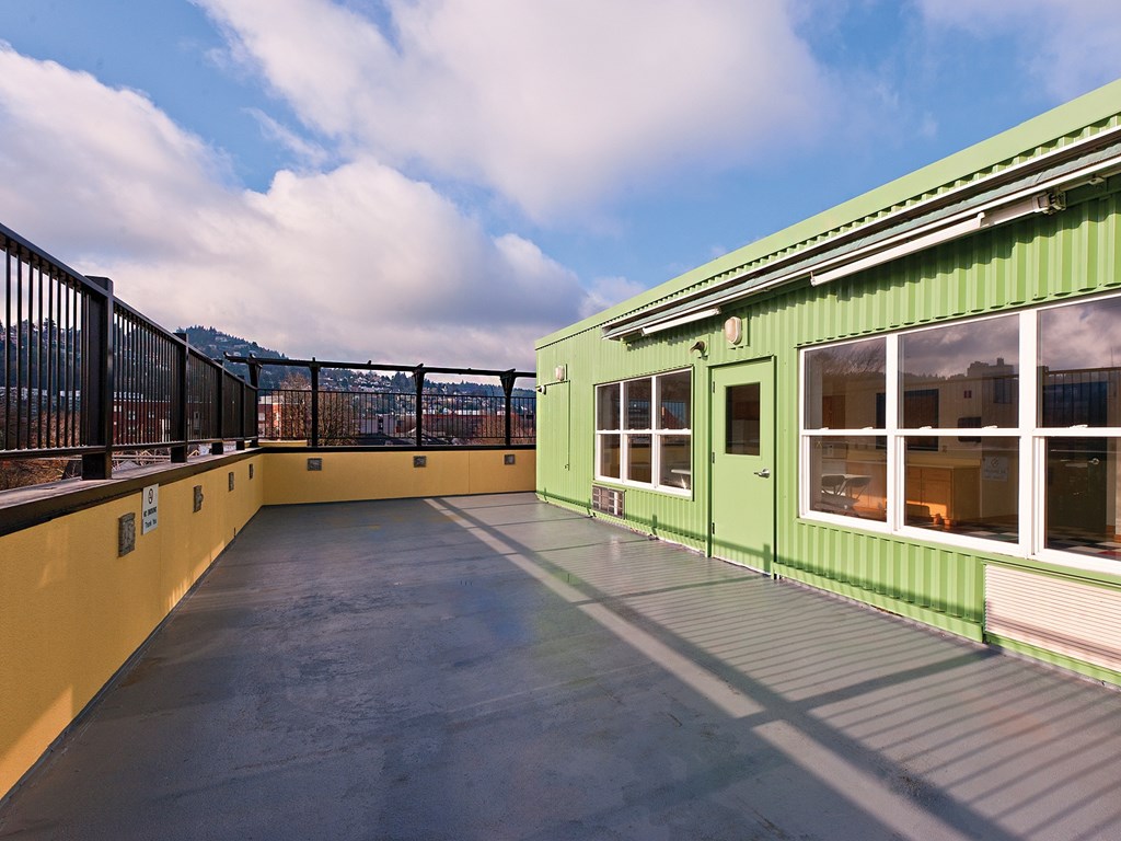 A green building with a balcony and a metal railing.