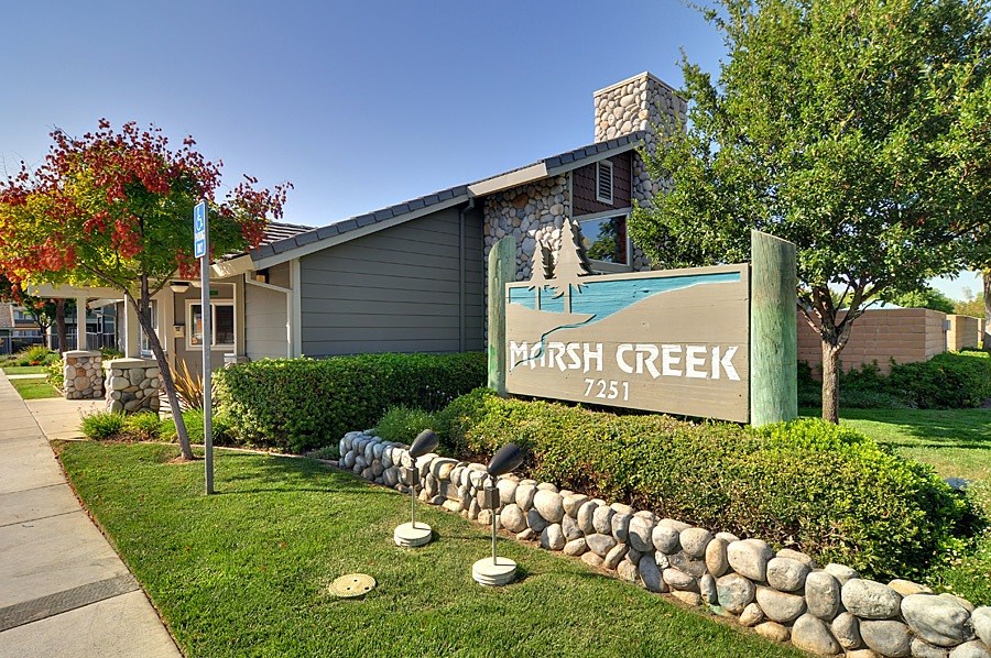 A sign that says Marsh Creek stands in front of a building.