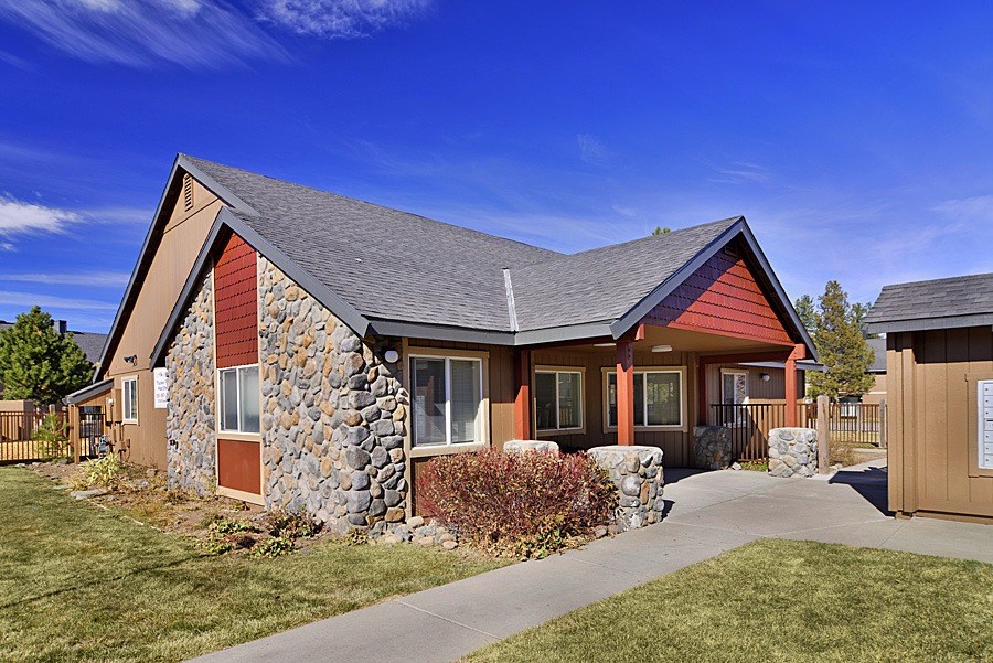 A house with a stone wall and a brown roof.