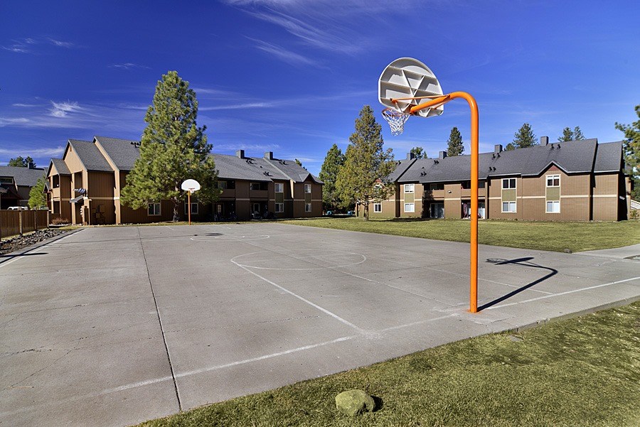 A basketball court with a hoop and a ball in the air.
