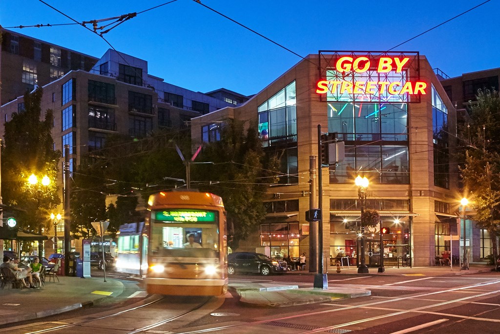 A streetcar is passing by a building with a neon sign that says "GO BY STREETCAR".