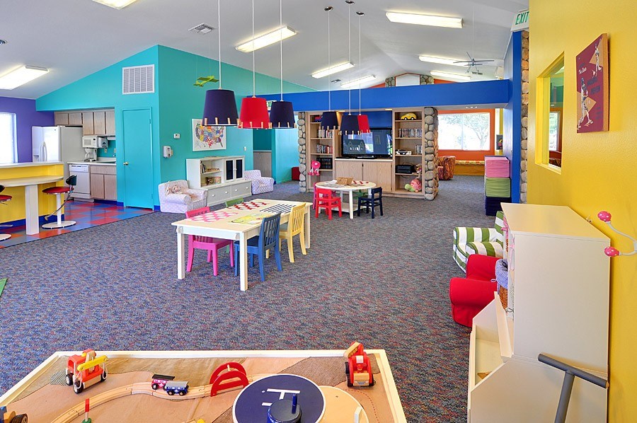 A playroom with a table and chairs and toy cars on the table.
