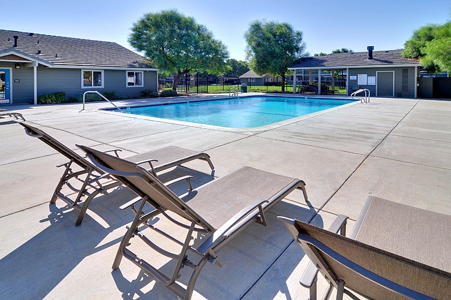 A pool with sun loungers in front of a house.