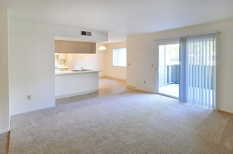 A spacious living room with a kitchen in the background.