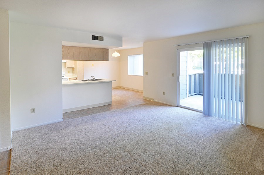 A spacious living room with a kitchen in the background.