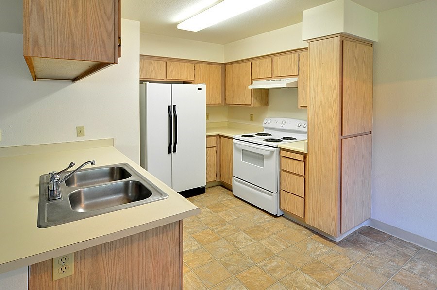 A kitchen with a white refrigerator, stove, and sink.