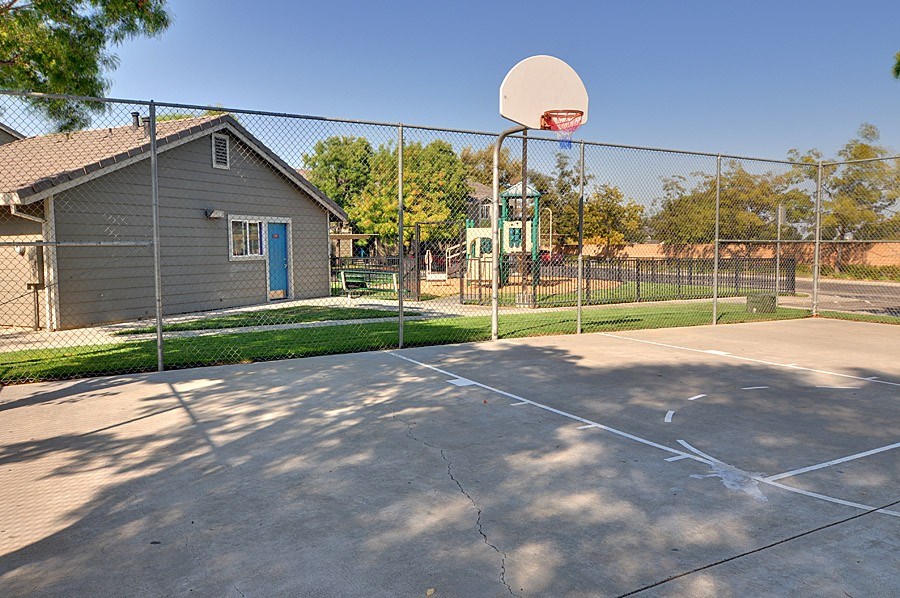 A basketball court with a basketball hoop and a small building in the background.