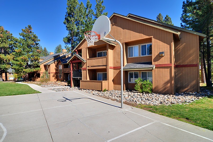 A basketball hoop is in front of a two-story apartment building.