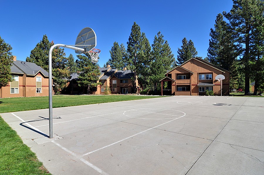 A basketball court with a hoop and a house in the background.