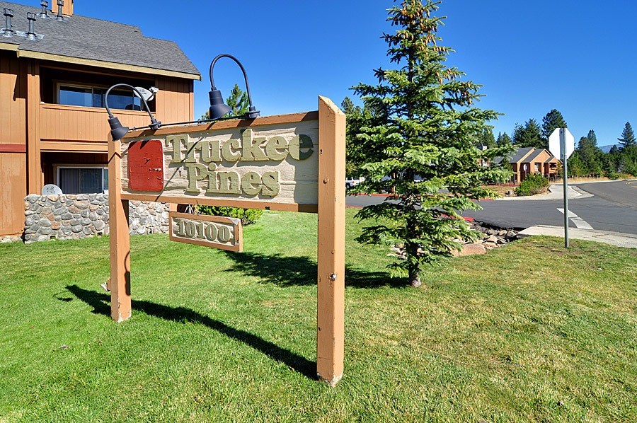 A wooden sign that says "Forked Pines" stands in a grassy area.