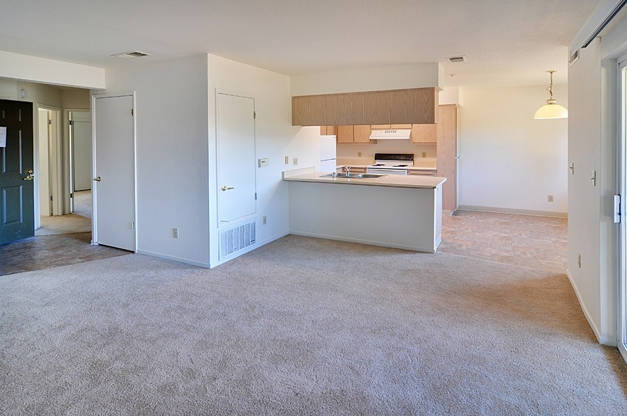 A large, empty room with a kitchenette in the background.