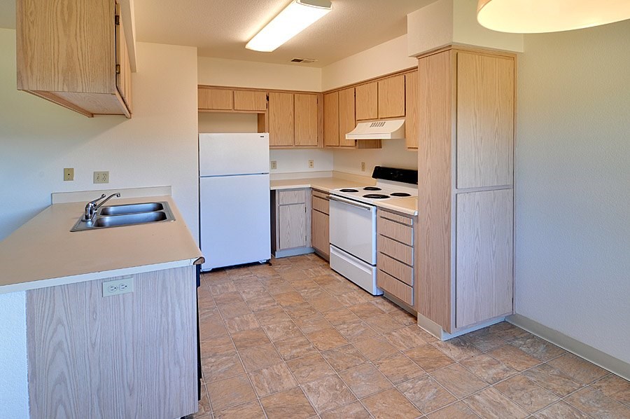 A kitchen with a white refrigerator, white oven, and wooden cabinets.