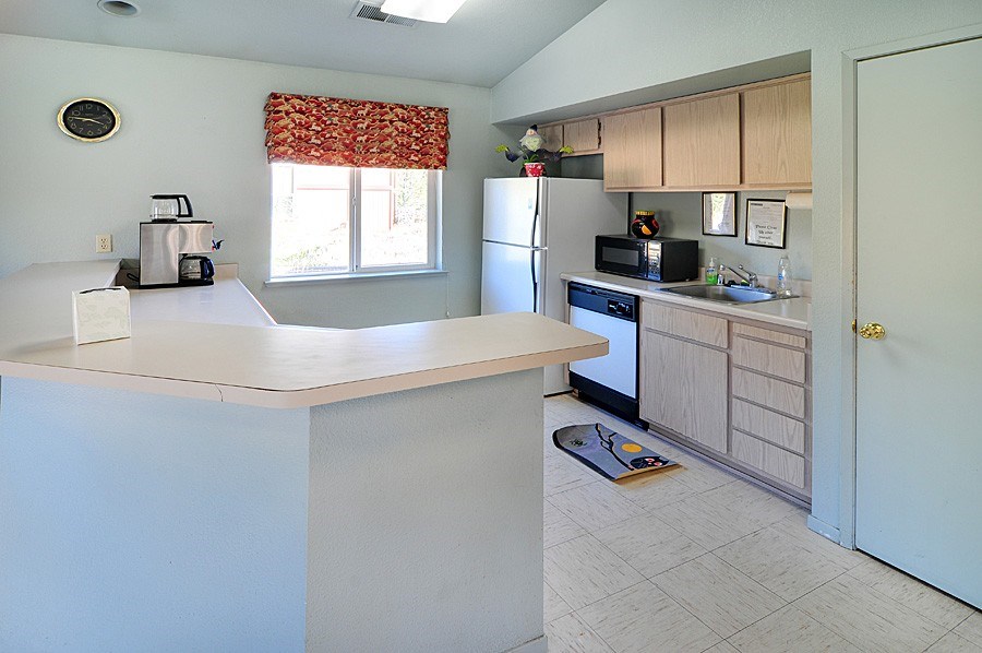 A kitchen with a white counter top and a refrigerator.