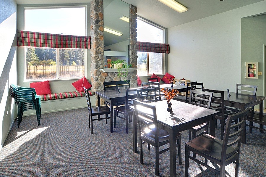 A room with a table and chairs and a window with a red and black plaid curtain.
