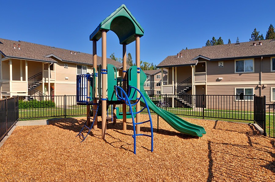 A playground with a green slide and a blue swing set.
