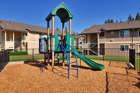 A playground with a green slide and a blue swing set.