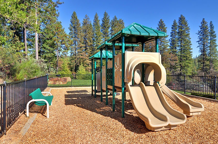 A playground with a green roofed structure and a slide.