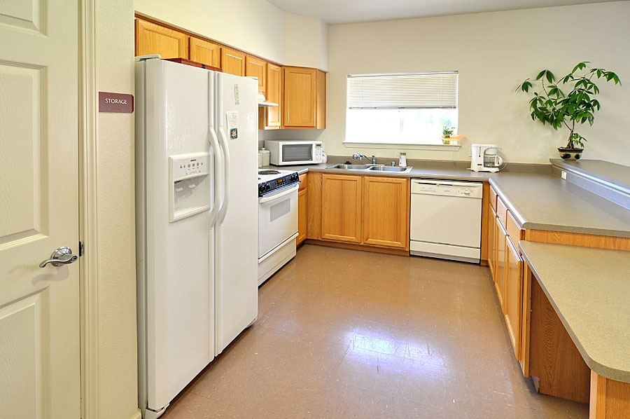 A kitchen with a refrigerator, oven, microwave, and sink.