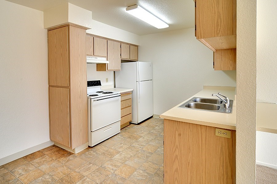A kitchen with a refrigerator, sink, and oven.