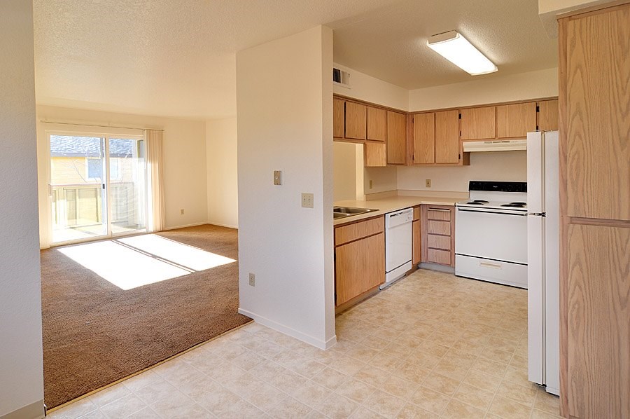 A kitchen with white appliances and wooden cabinets.