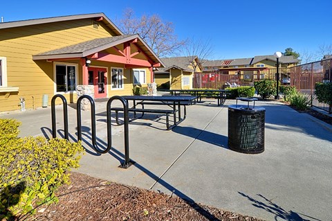 A yellow building with a red door and a black trash can in front of it.