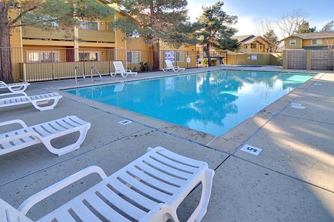 A pool surrounded by white lounge chairs.