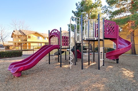 A playground with a red slide and a purple slide.