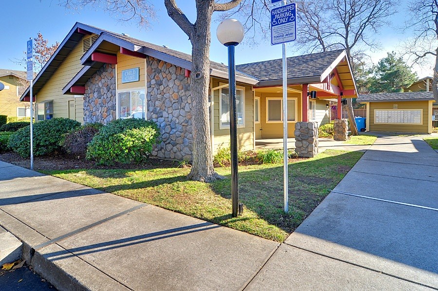 A house with a stone wall and a tree in front.