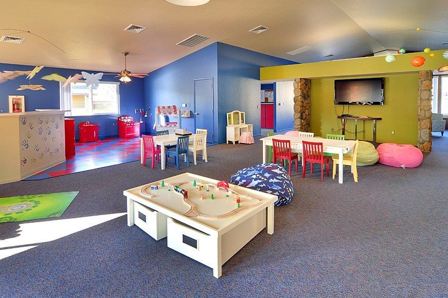 A playroom with a blue carpet and a white table.
