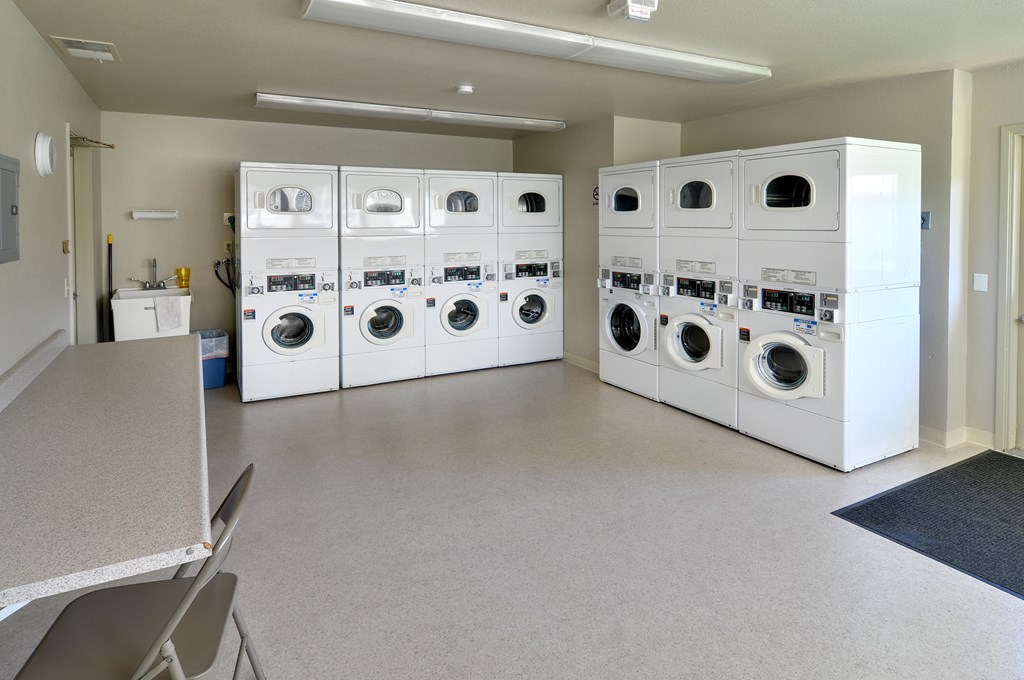 A laundry room with a row of washers and dryers.