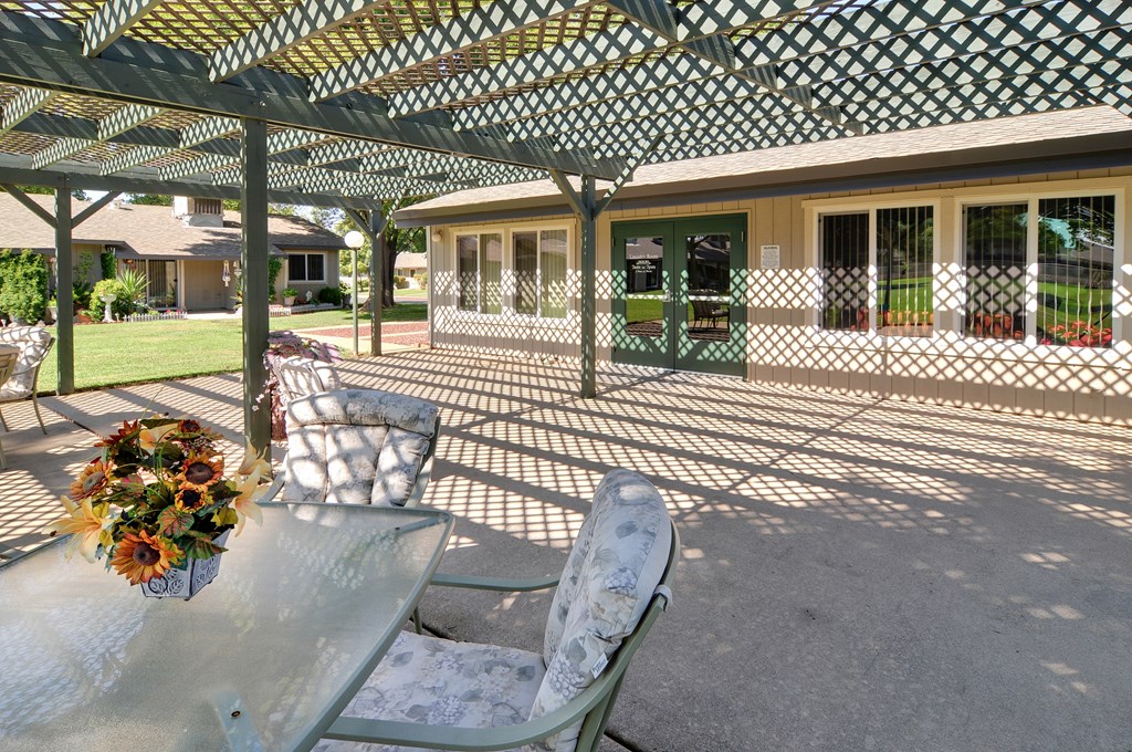 A patio with a table and chairs under a green and white umbrella.